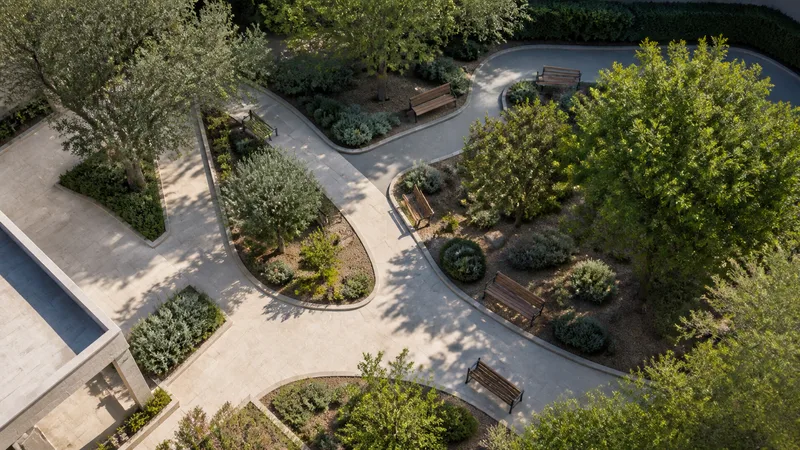 Jardín tranquilo de un centro residencial con senderos accesibles y bancos vacíos bajo los árboles