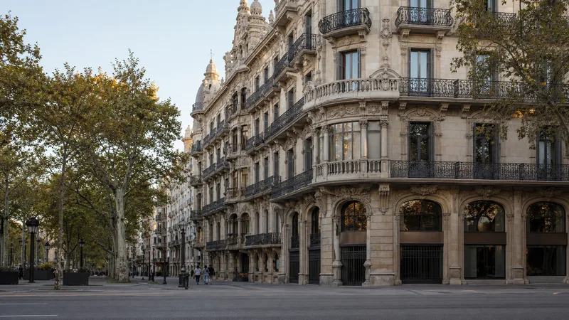 Chaflán arbolado del paseo de Gràcia con fachadas de piedra y balcones de hierro