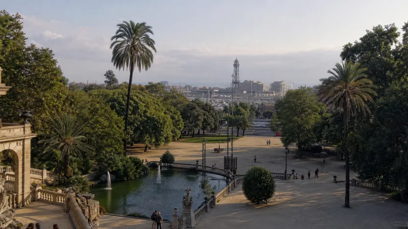 Parque arbolado de la Ciutadella con el puerto de Barcelona visible a lo lejos