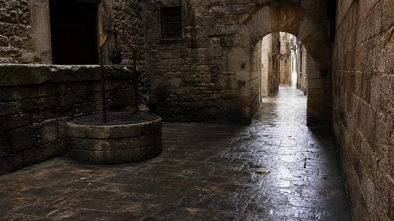 Arco y calle de piedra del Barri Gòtic después de la lluvia, sin personas reconocibles