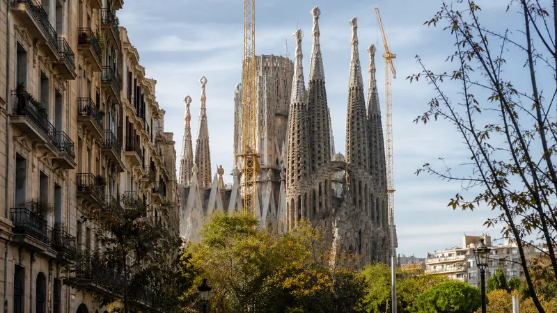 Sagrada Família entre fachadas residenciales y árboles del Eixample durante una mañana clara