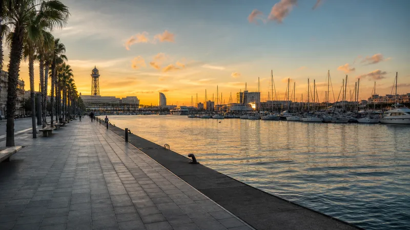 Paseo de Port Vell con veleros amarrados y el frente marítimo de Barcelona al atardecer