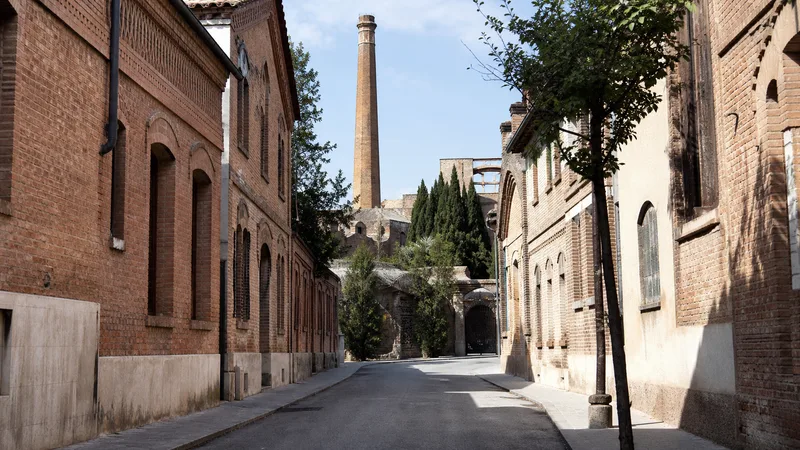 Calle de viviendas obreras de ladrillo y chimenea de la Colònia Güell