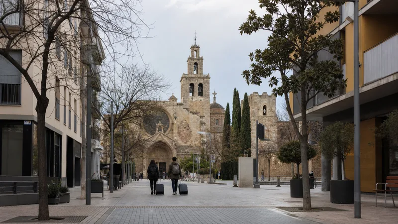 Eje peatonal de Sant Cugat con el monasterio al fondo y dos viajeros