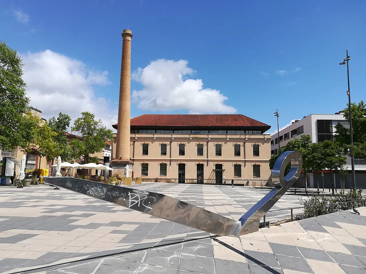 Plaça de Cal Font con las tijeras, la chimenea y la Biblioteca Central