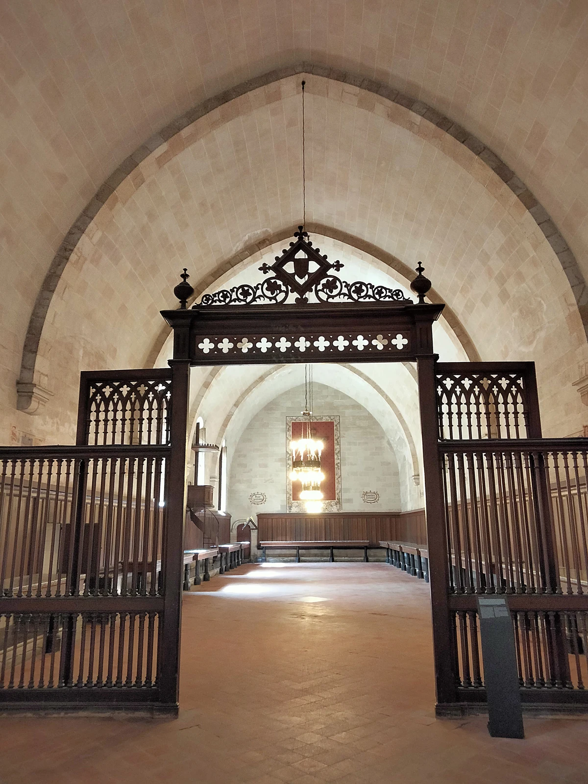 Refectorio de Pedralbes con bancos, mesas y celosía de madera en la entrada