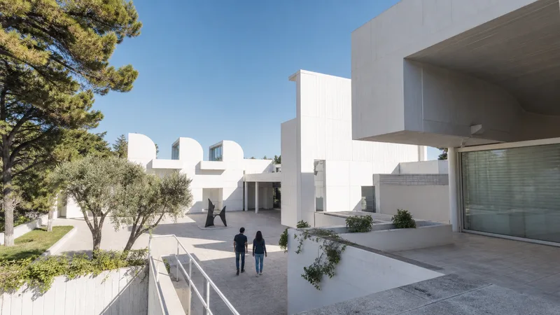 Arquitectura blanca, patios y vegetación de la Fundació Joan Miró en Montjuïc, con dos visitantes de espaldas