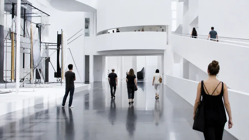 Atrio blanco de un museo de arte contemporáneo con rampas y visitantes
