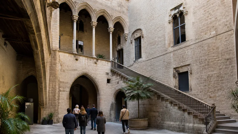 Patio gótico de piedra de los palacios que albergan el Museu Picasso con visitantes de espaldas