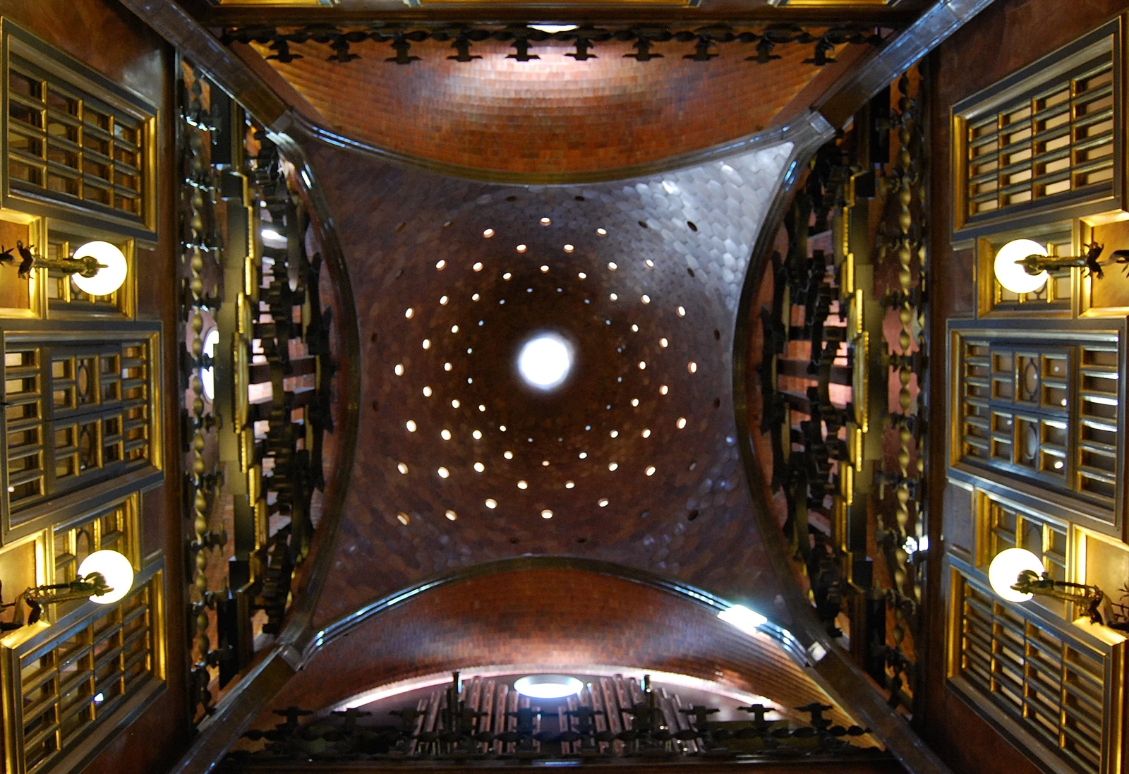Cúpula perforada, arcos y galerías del salón central del Palau Güell vistos desde abajo