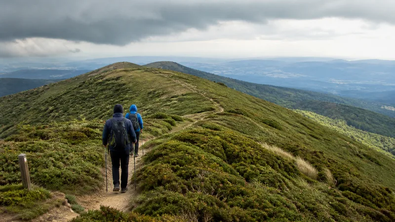 Dos senderistas de espaldas por una cresta redondeada del Montseny bajo nubes bajas