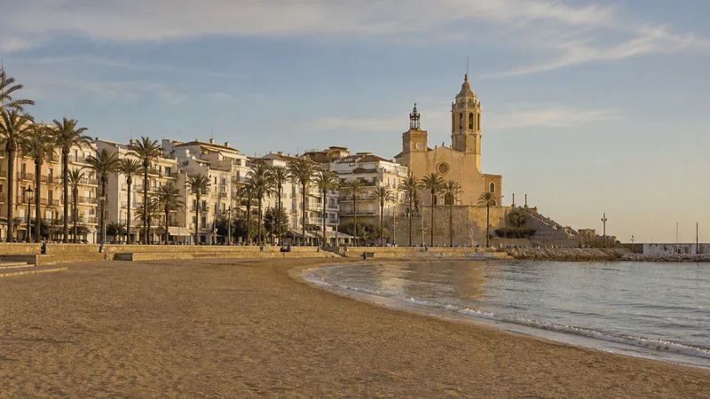 Playa y paseo de Sitges con el casco blanco y la iglesia sobre el promontorio