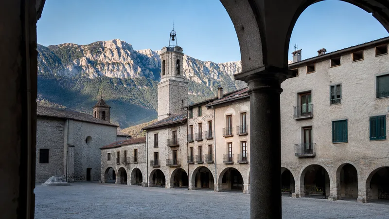 Plaza porticada de Bagà con arquitectura de piedra y el Cadí al fondo