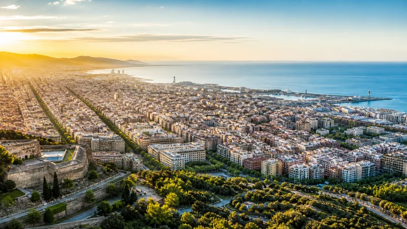 Vista editorial de Barcelona que conecta Eixample, Ciutat Vella, Montjuïc y el mar al amanecer, sin personas reconocibles