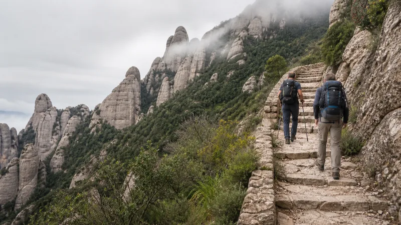 Senderistas ascendiendo por peldaños de piedra entre las agujas de Montserrat