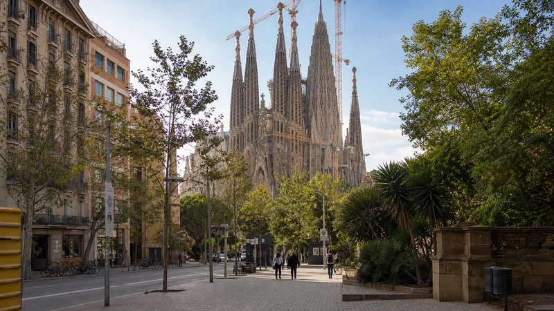 Llegada peatonal a la Sagrada Família desde la avenida de Gaudí, con arbolado, aceras y grúas de obra