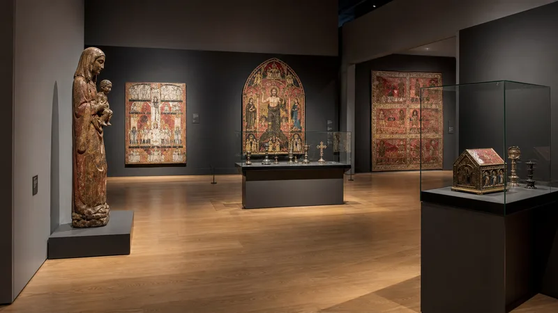 Sala del Museu Episcopal de Vic con escultura, pintura y orfebrería medieval bajo luz controlada