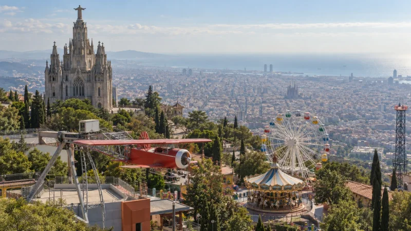 Vista panorámica del parque del Tibidabo con el Templo del Sagrado Corazón, el Avió y atracciones sobre Barcelona